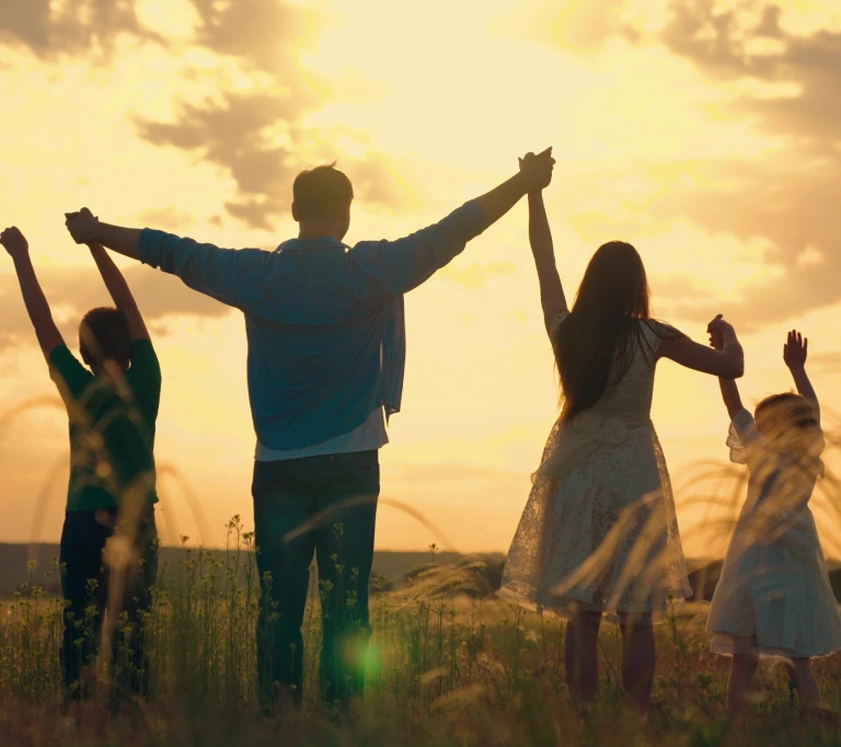a group of people standing in a field with their arms raised