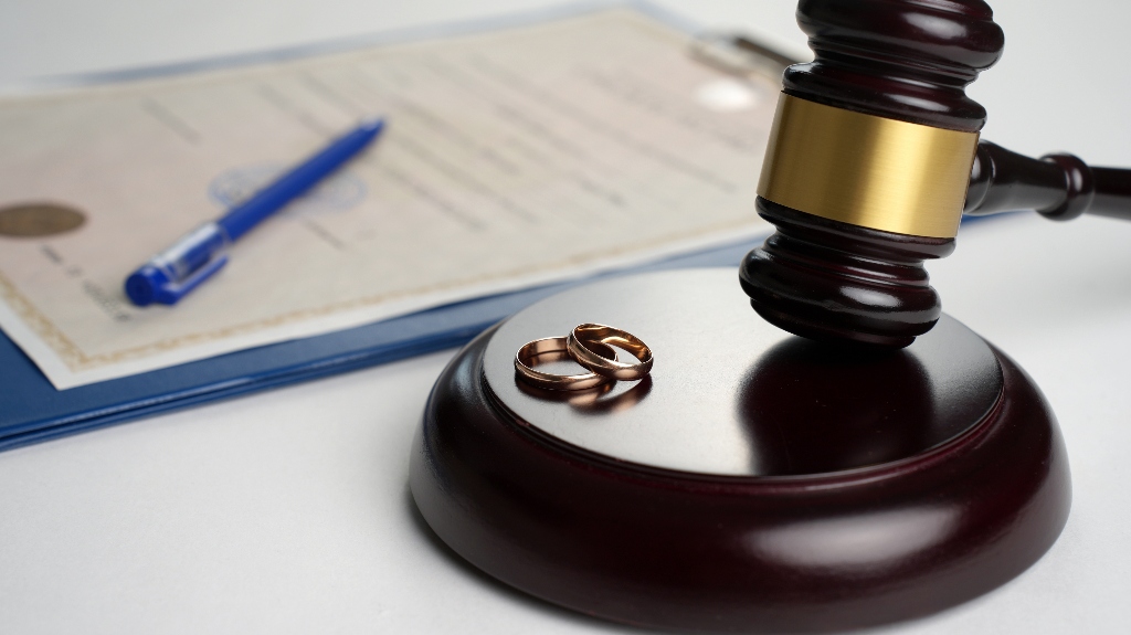 Judge gavel with wedding rings and divorce decree