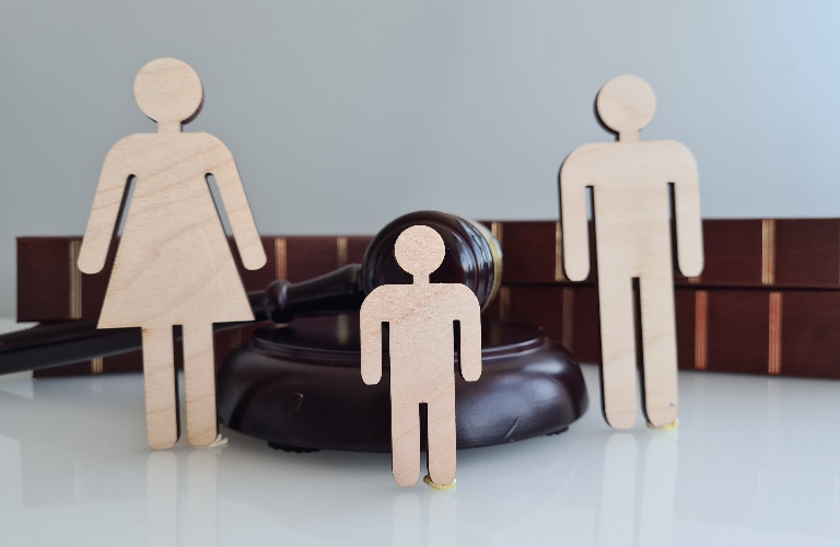 Wooden figures representing a Family near a Gavel and Law Books