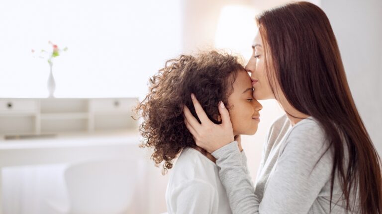 mother kisses daughter on the forehead