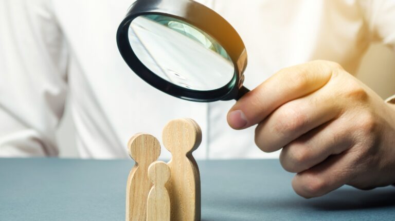 person looks at family figures through a magnifying glass