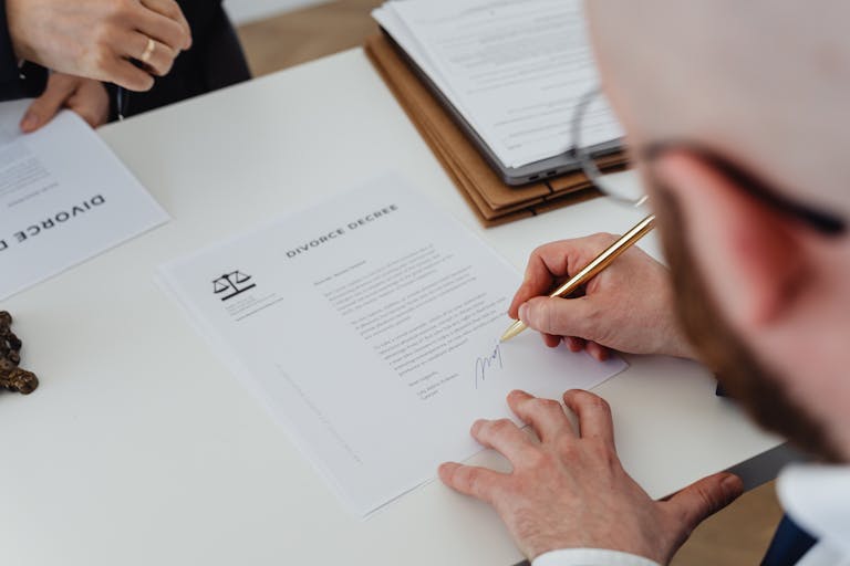 Close-up of a person signing a divorce decree on a desk.