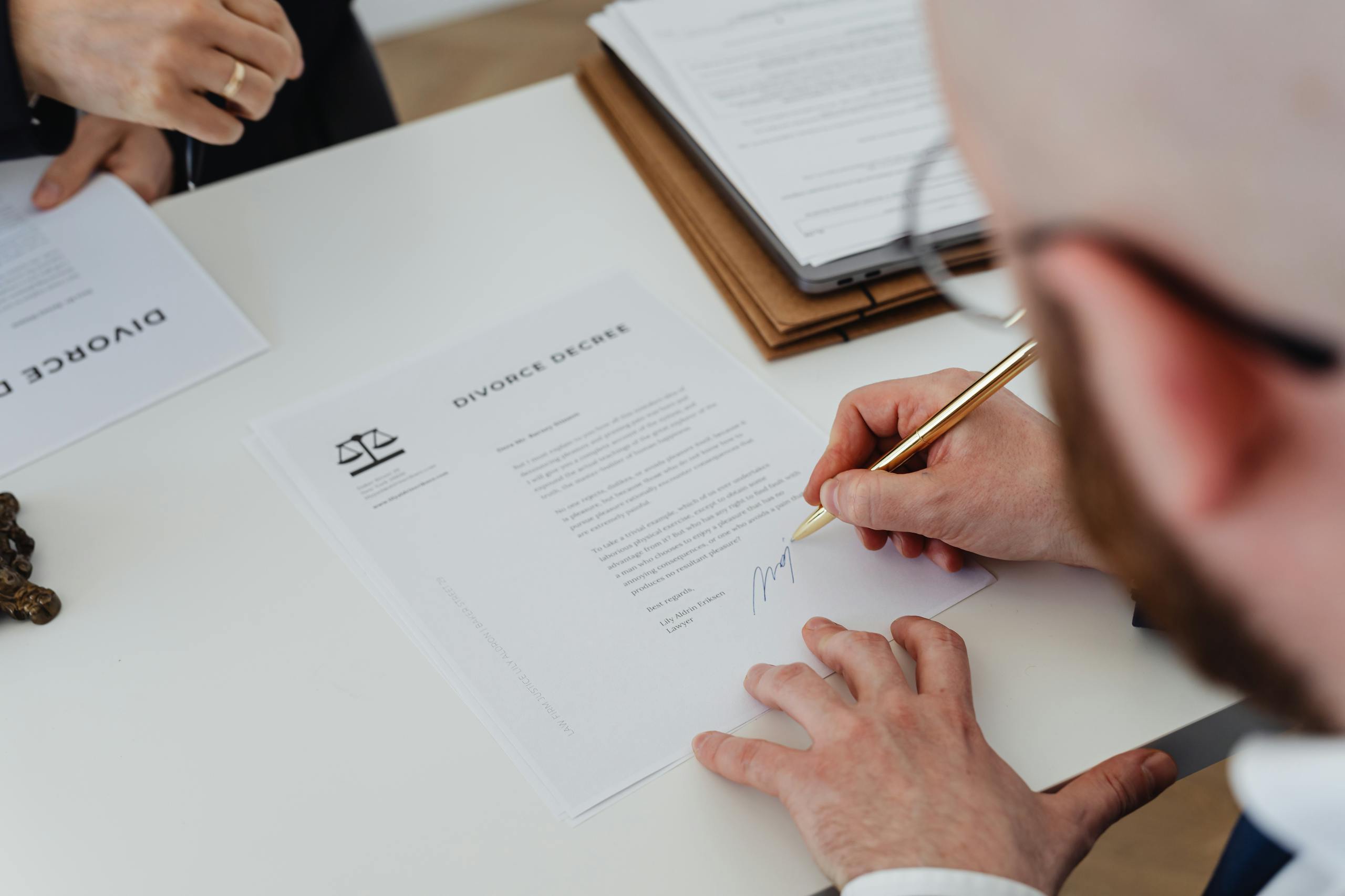 Close-up of a person signing a divorce decree on a desk.